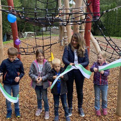 Spielplatzeinweihung Altersberg. Kinder schneiden zusammen mit der Bürgermeisterin Sabine Welte-Hauff ein Band durch.