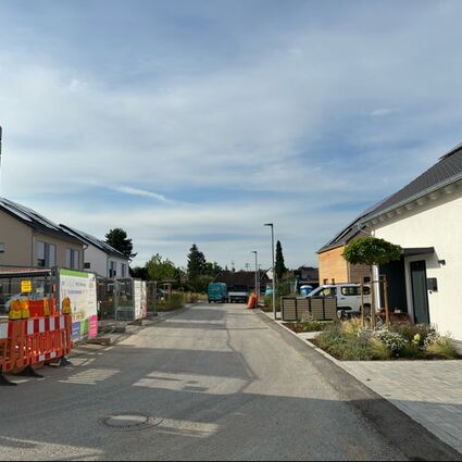 Blick in eine neugebaute Straße mit Neubauhäusern und einem Kran