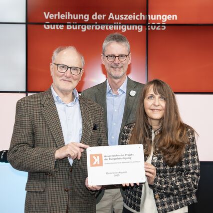 Preisverleihung Auszeichnung gute Bürgerbeteiligung 2025. Zwei Männer überreichen der Welte-Hauff eine Auszeichnung.