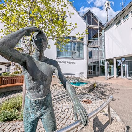 Eine Bronzefigur steht vor dem Aspacher Rathaus